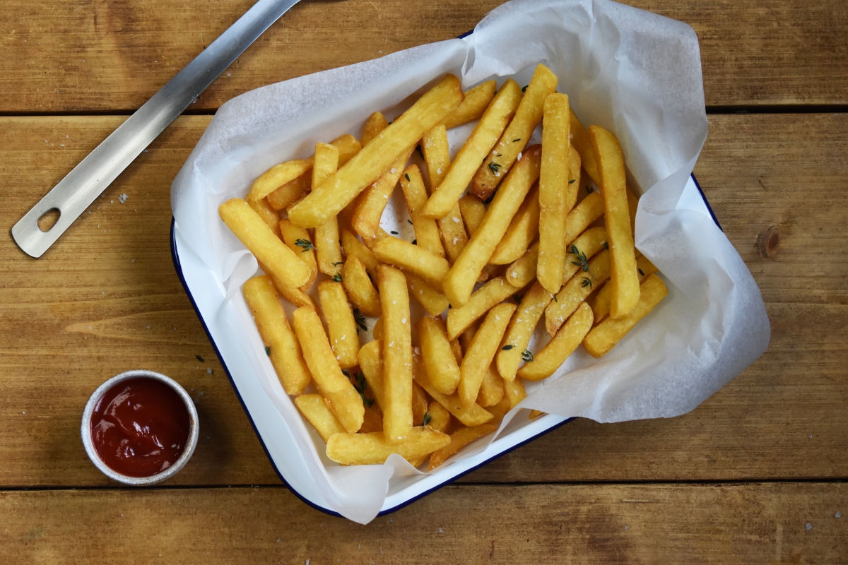 Pommes in einer Schale serviert auf holztisch- illustriert zur Geschichte der Pommes und wer Pommes erfunden hat