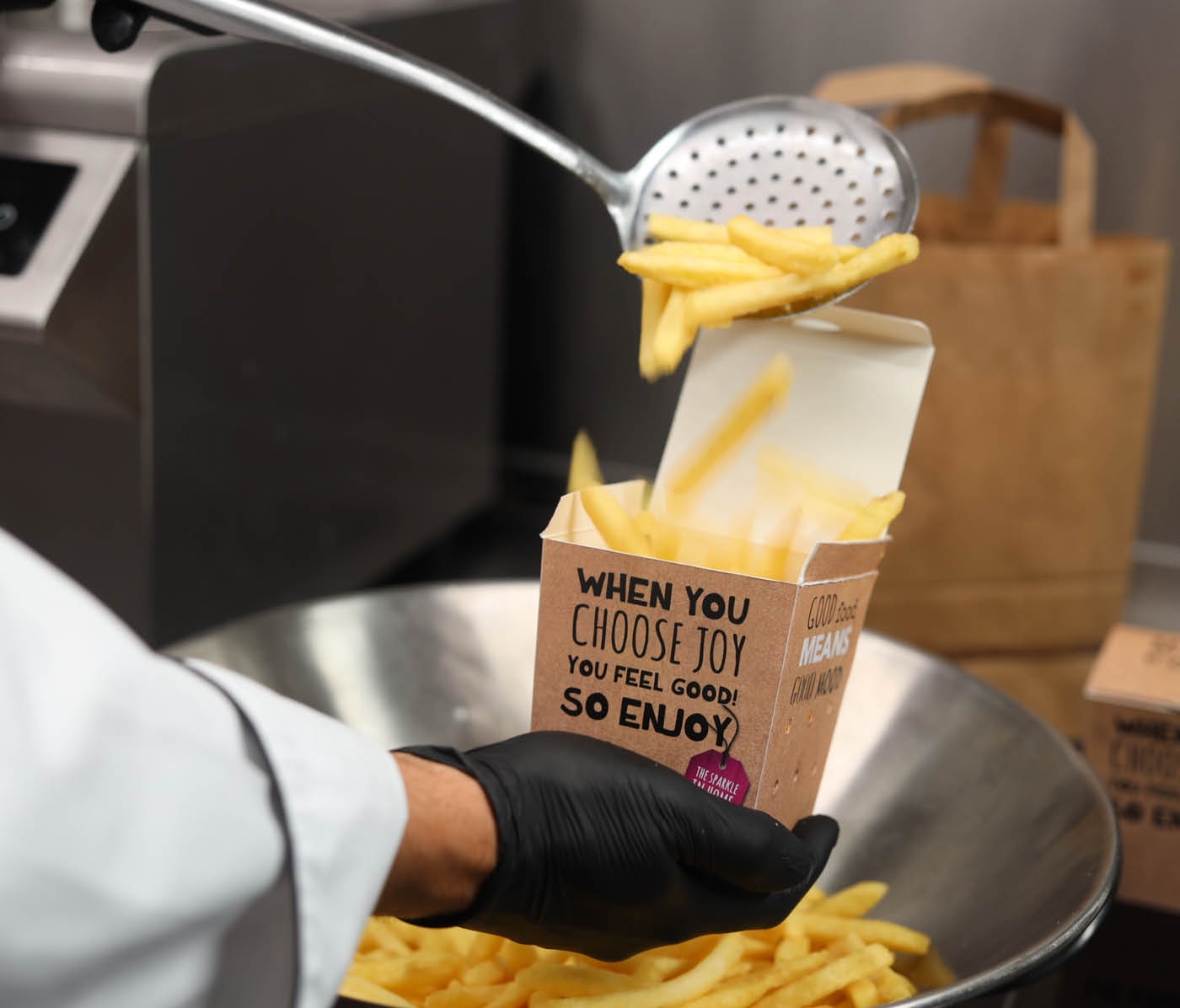 Chef füllt Pommes in Liefer-Verpackung