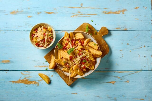 lets top it alles kaas getoppte pommes auf blauem tisch und holzbrett
