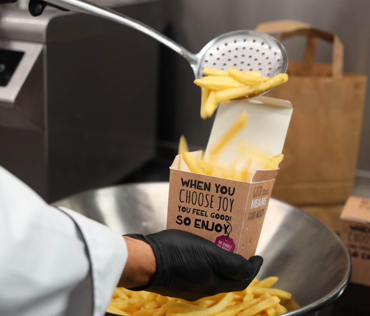 Chef füllt Pommes in Liefer-Verpackung