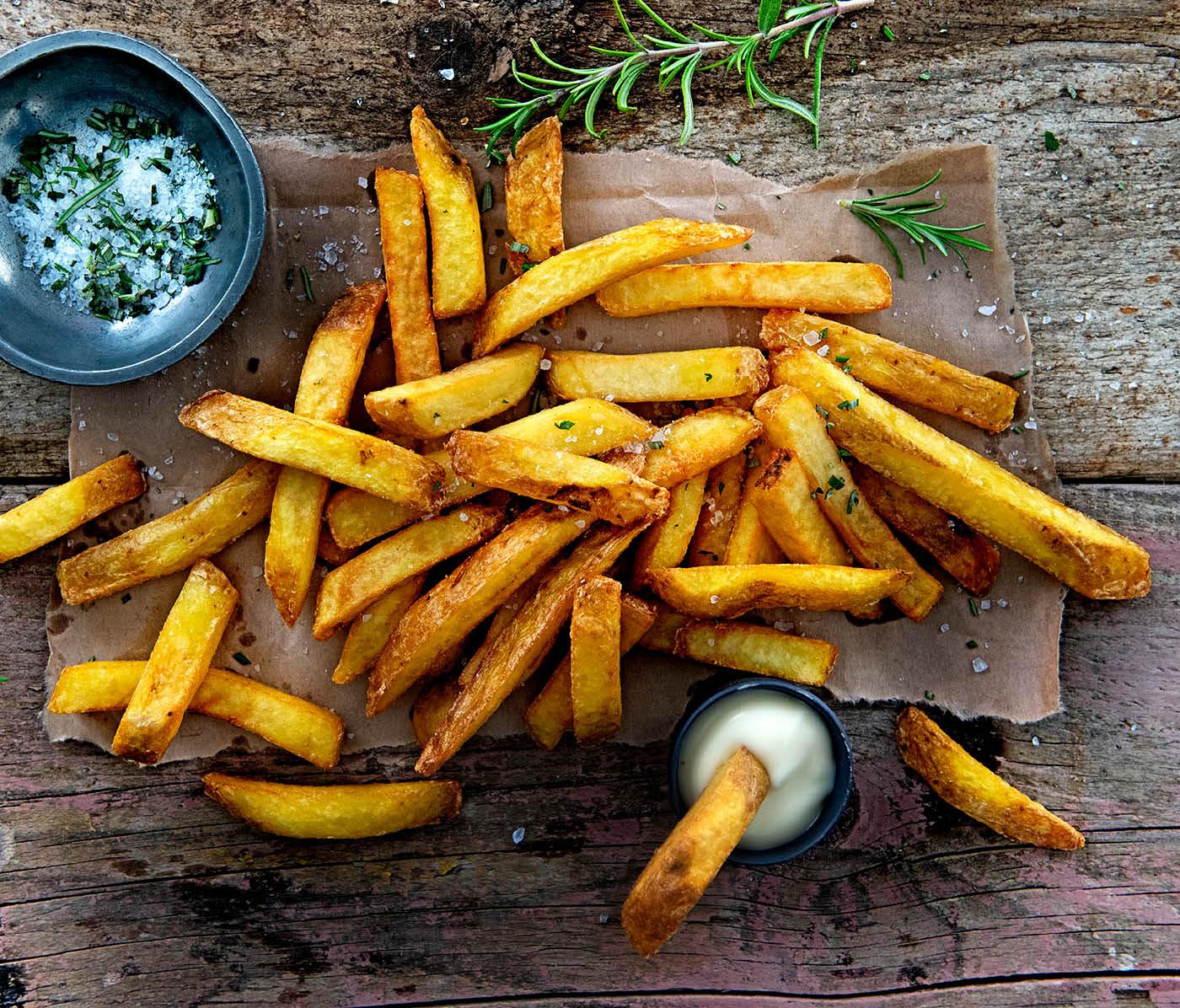 Pommes auf holzbrett serviert mit dip Schälchen