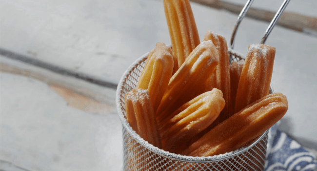 churros in fritteusensieb serviert auf weissem tisch- churros kaufen