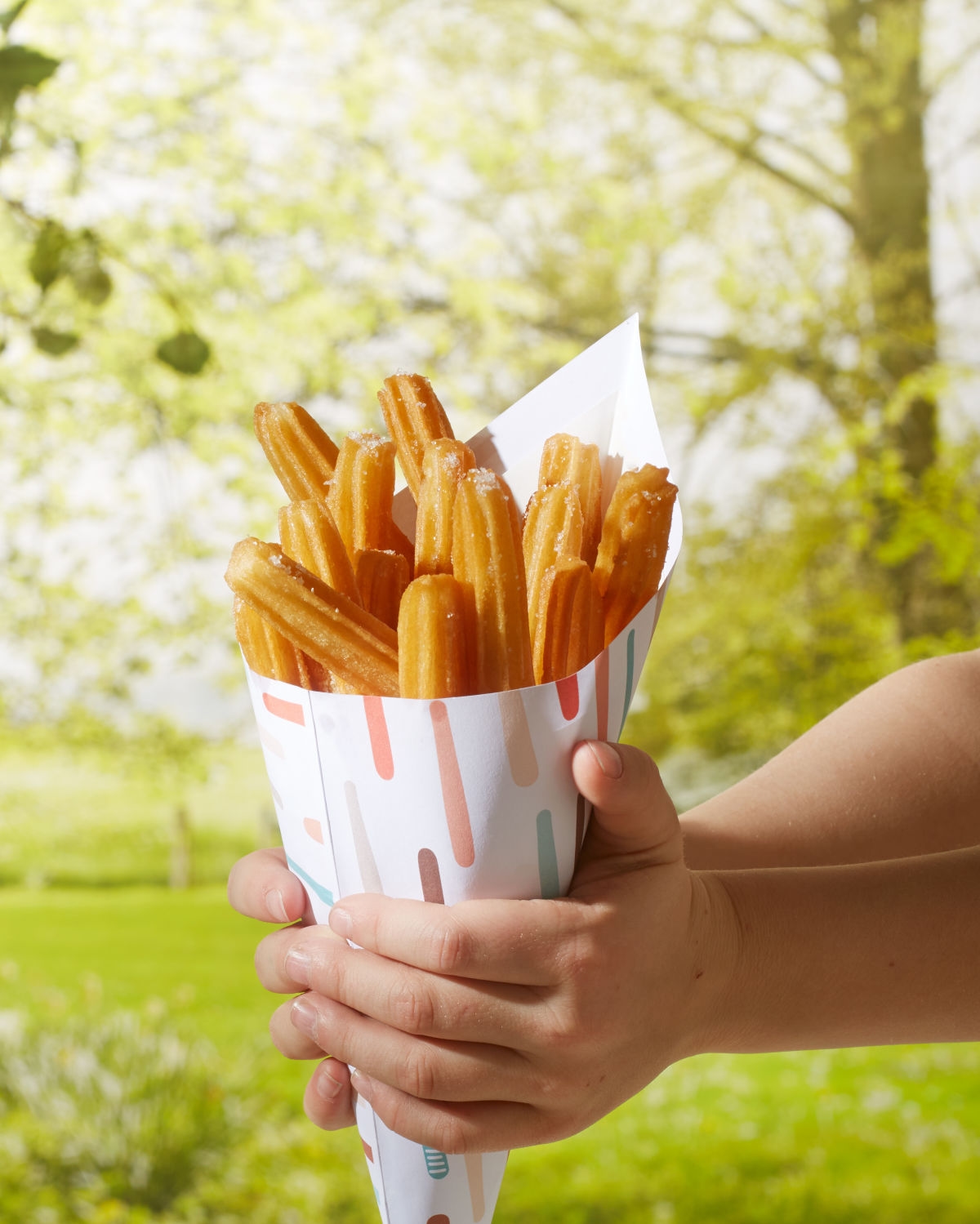 Tüte Churros in Kinderhänden in der natur fotografiert