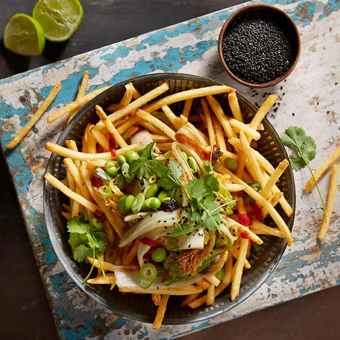 Pommes aus der Heissluftfritteuse serviert mit Toppings auf Holzbrett von oben fotografiert