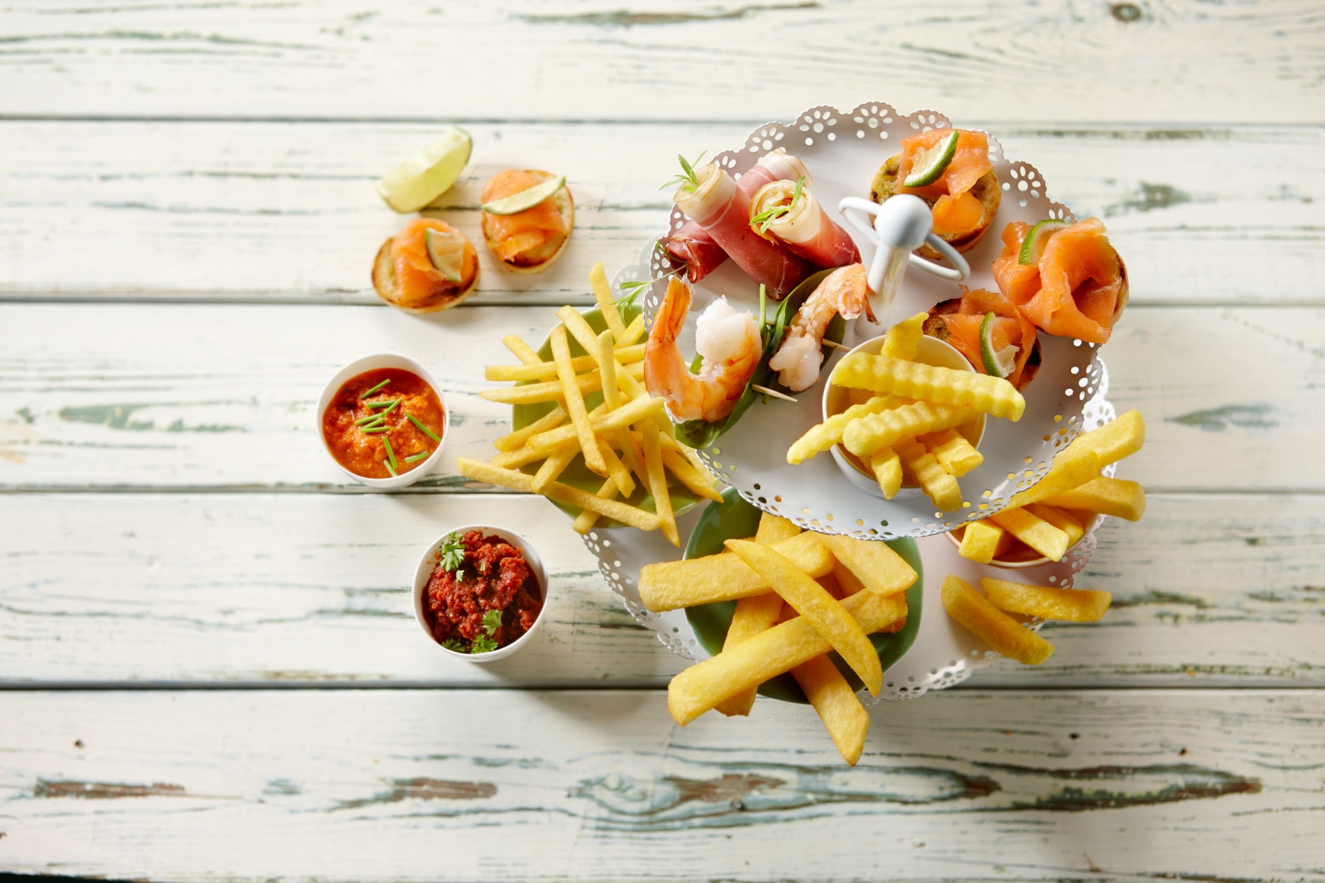 pommes und häppchen auf hochteller angerichtet auf hellem hintergrund